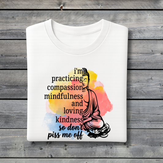 White t-shirt with Buddha graphic and motivational text on a wooden surface